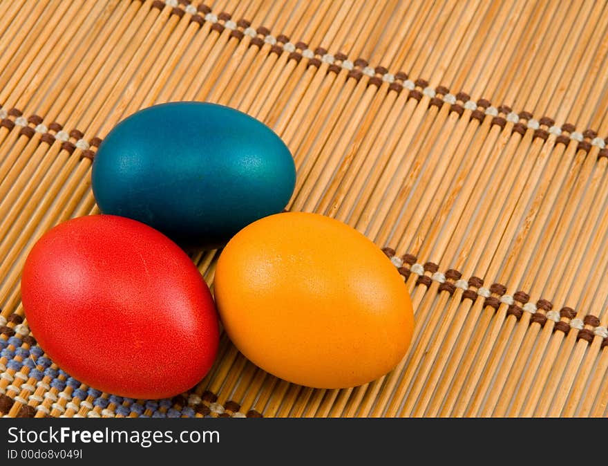 Three easter eggs on bamboo mat