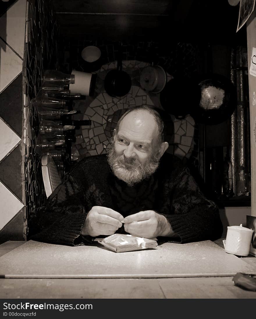 Man with grey beard rolling a cigarette. Man with grey beard rolling a cigarette