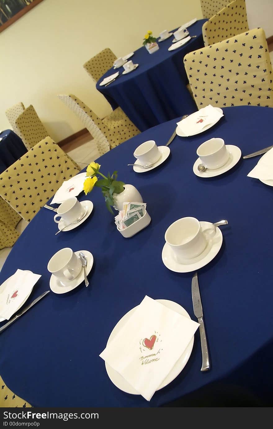 Breakfast in a restaurant room with plates, cups, tables and chairs