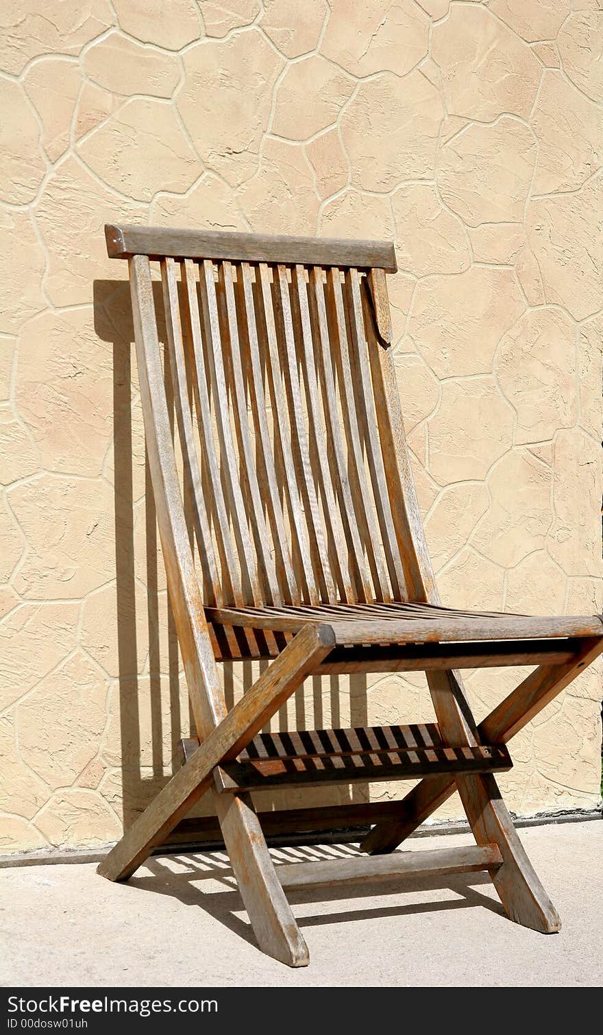 An empty wooden chair casting shadows on a wall