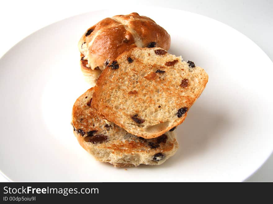 Traditional hot cross buns whole and sliced close-up on the plate