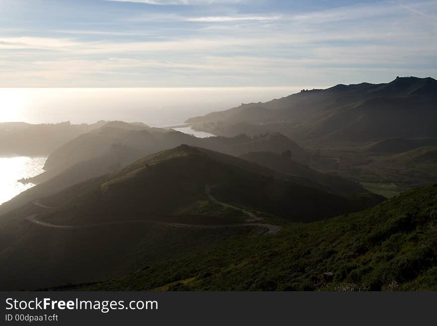 Ocean view with hills in sunset mist