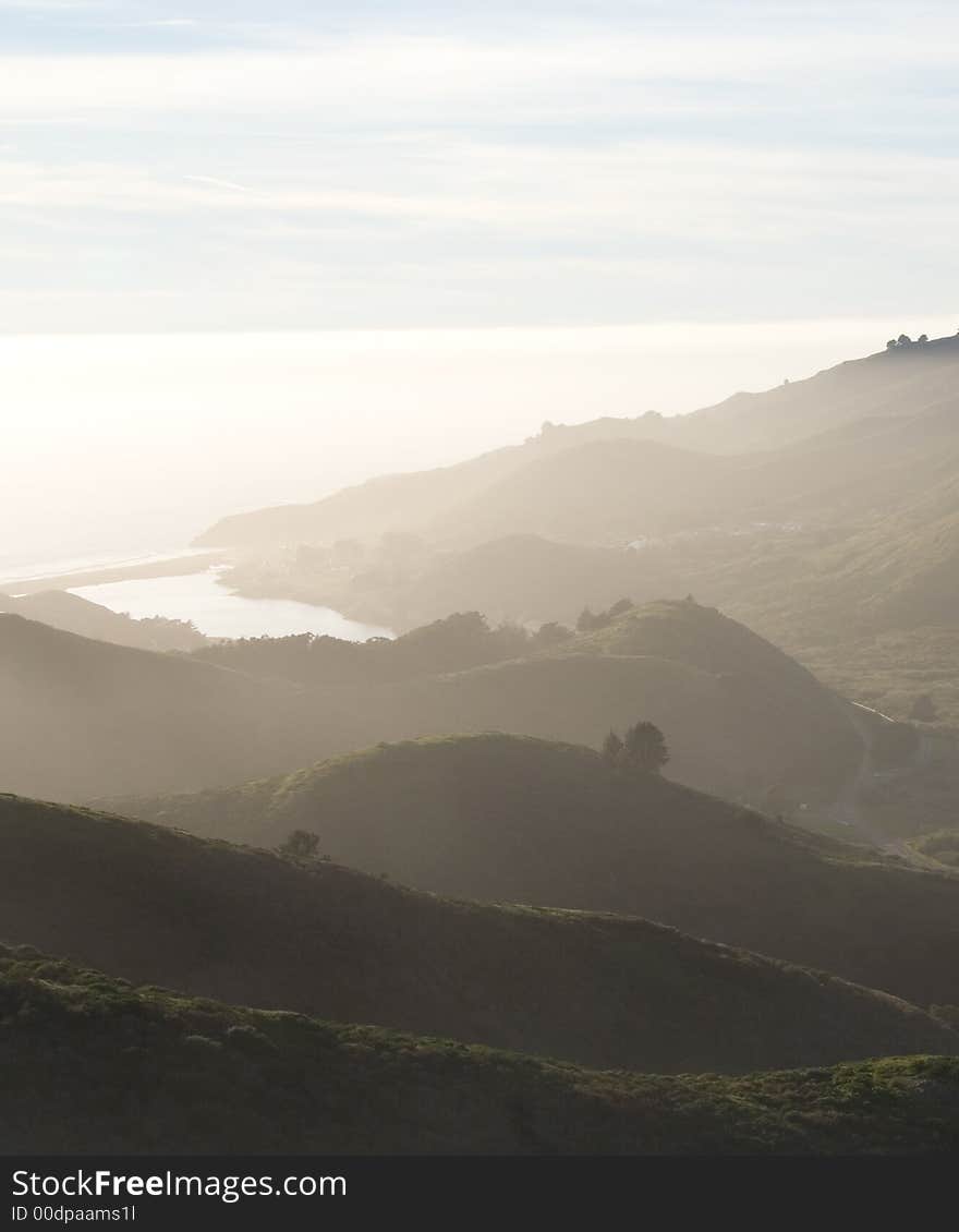 A view of pacific ocean over green hills during sunset. A view of pacific ocean over green hills during sunset