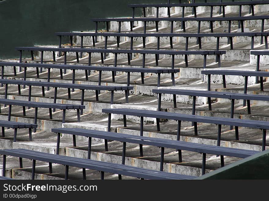 Blue Benches On A Grey Concrete Ground In Rows, Stadium Seats. Blue Benches On A Grey Concrete Ground In Rows, Stadium Seats