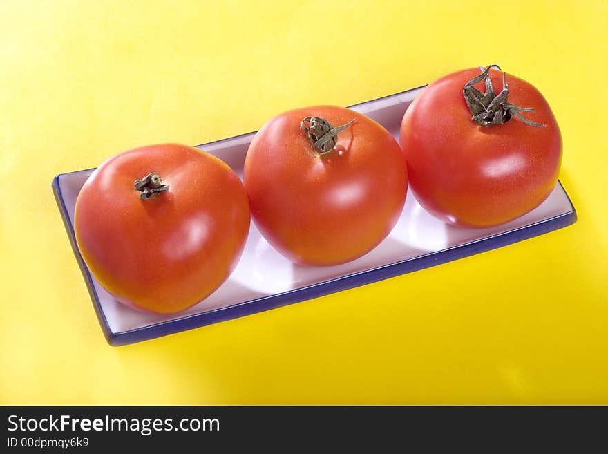 A photo of three tomatoes on the plate. A photo of three tomatoes on the plate