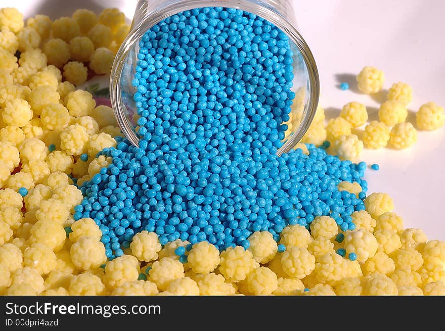 Small blue candies in a small glass on a saucer with yellow candies