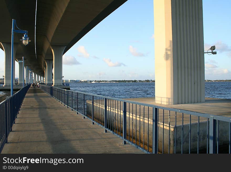 Tall Bridge over Fishing Recreation Area. River scenic with blue sky and clouds. Horizon visible. Tall Bridge over Fishing Recreation Area. River scenic with blue sky and clouds. Horizon visible.