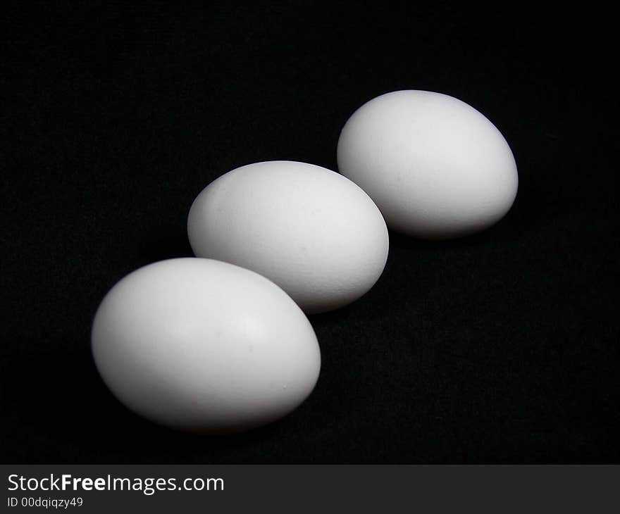 Three large white eggs on black. Three large white eggs on black