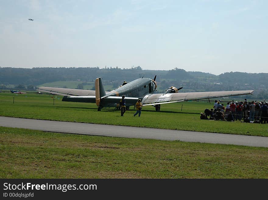 Swiss Military Propeller Airplane ready for takeoff on grass observed by spectators