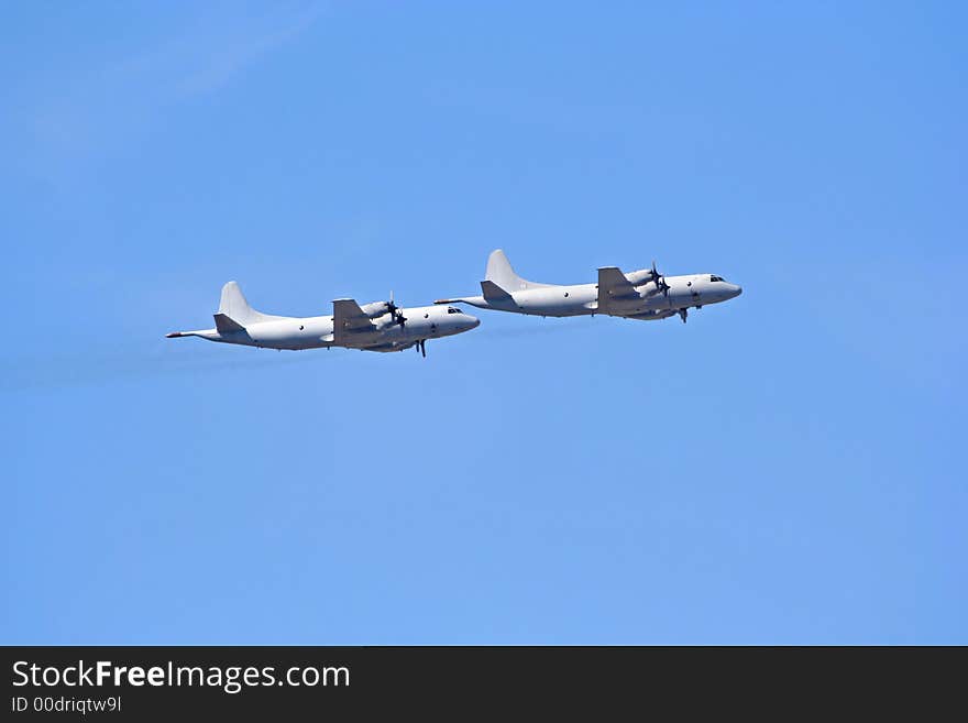 A pair of large military airplanes while on flight. A pair of large military airplanes while on flight