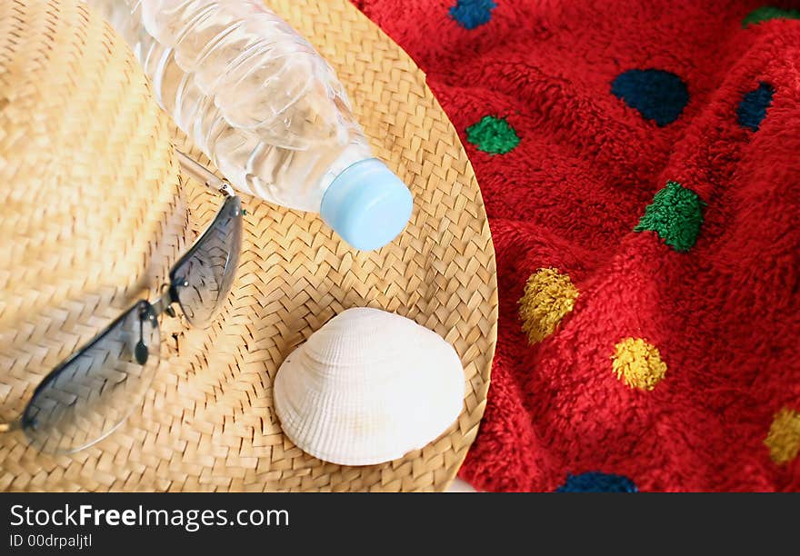 Still-life of things featured to holiday on the beach: straw-hat,sunglasses,towel,sparkling water and shell. Still-life of things featured to holiday on the beach: straw-hat,sunglasses,towel,sparkling water and shell