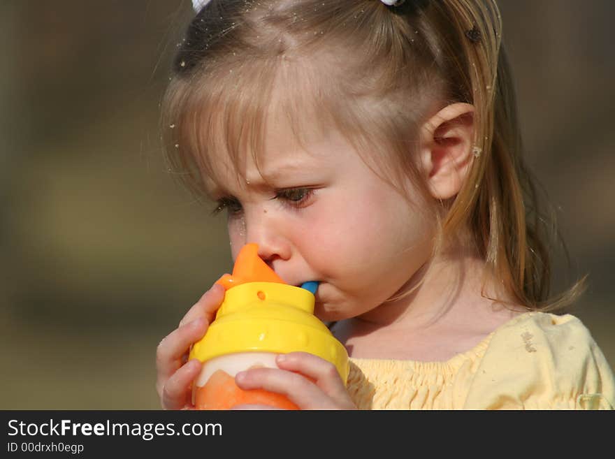 This is a close up of my two year old daughter getting something to drink after she has been playing in the sand. You can see the sand in her hair, and on her face. This is a close up of my two year old daughter getting something to drink after she has been playing in the sand. You can see the sand in her hair, and on her face.