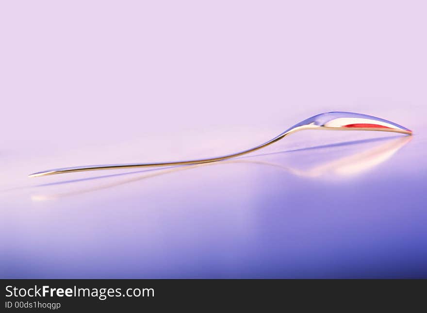 Dessert brilliant spoon on  glass surface and  blue background. Dessert brilliant spoon on  glass surface and  blue background