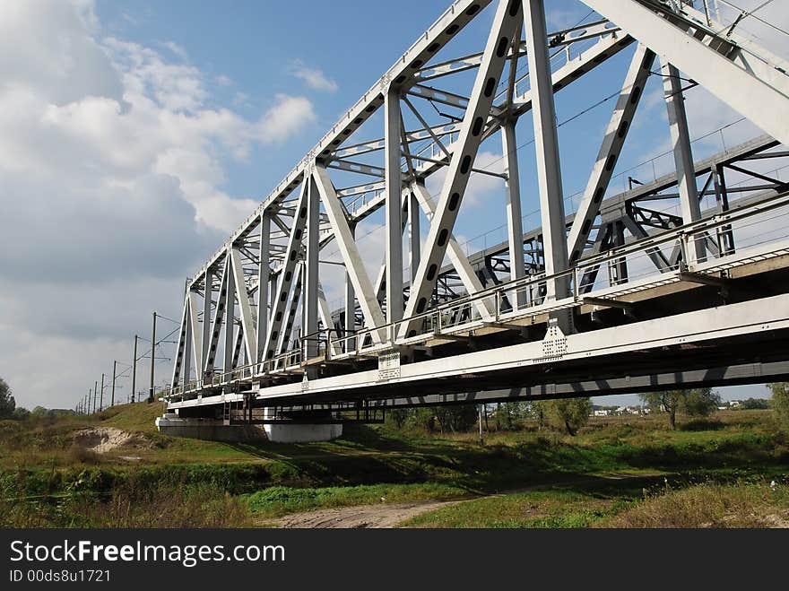 White grey railway bridge over small river with green banks