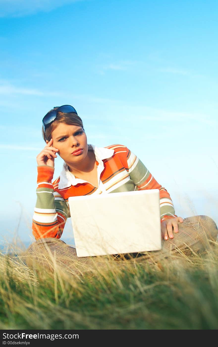 Young business woman relaxing, working on laptop computer on meadow. Young business woman relaxing, working on laptop computer on meadow