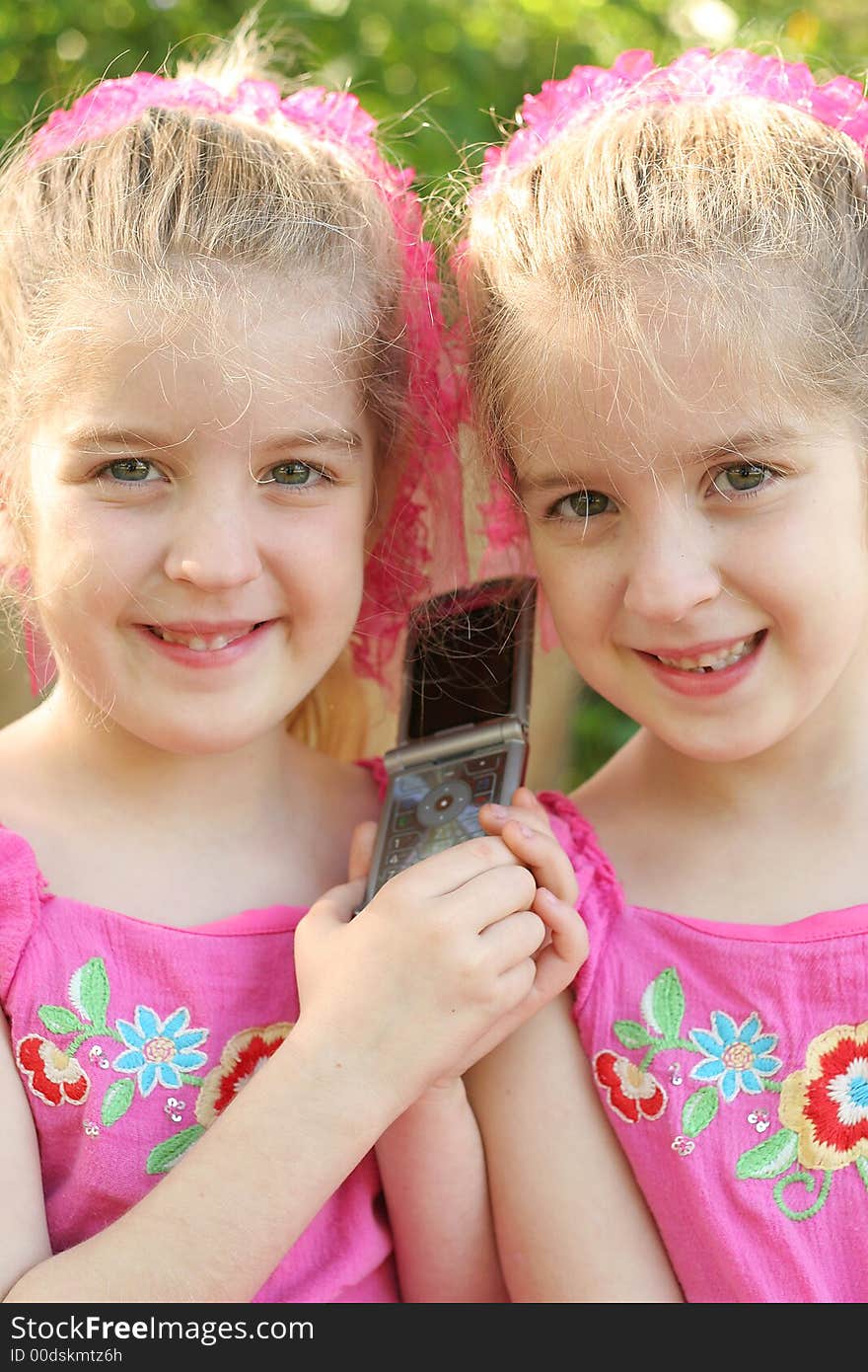 Shot of twin girls sharing a cell phone call vertical