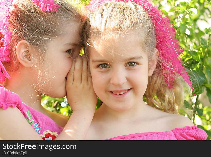 Shot of twin sisters sharing a secret looking