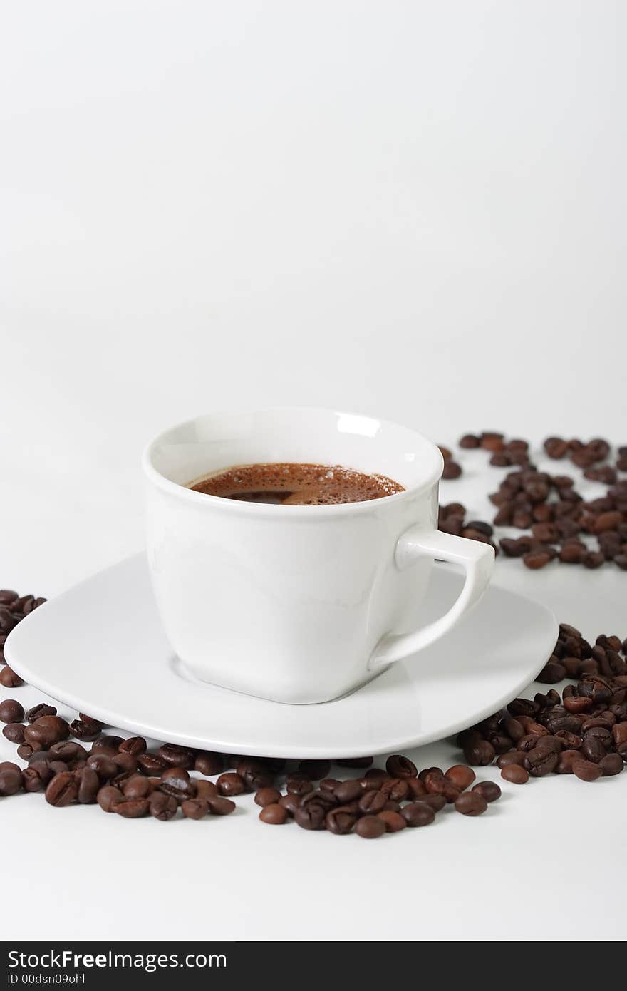 White coffee cup on a plate and coffee beans. White coffee cup on a plate and coffee beans