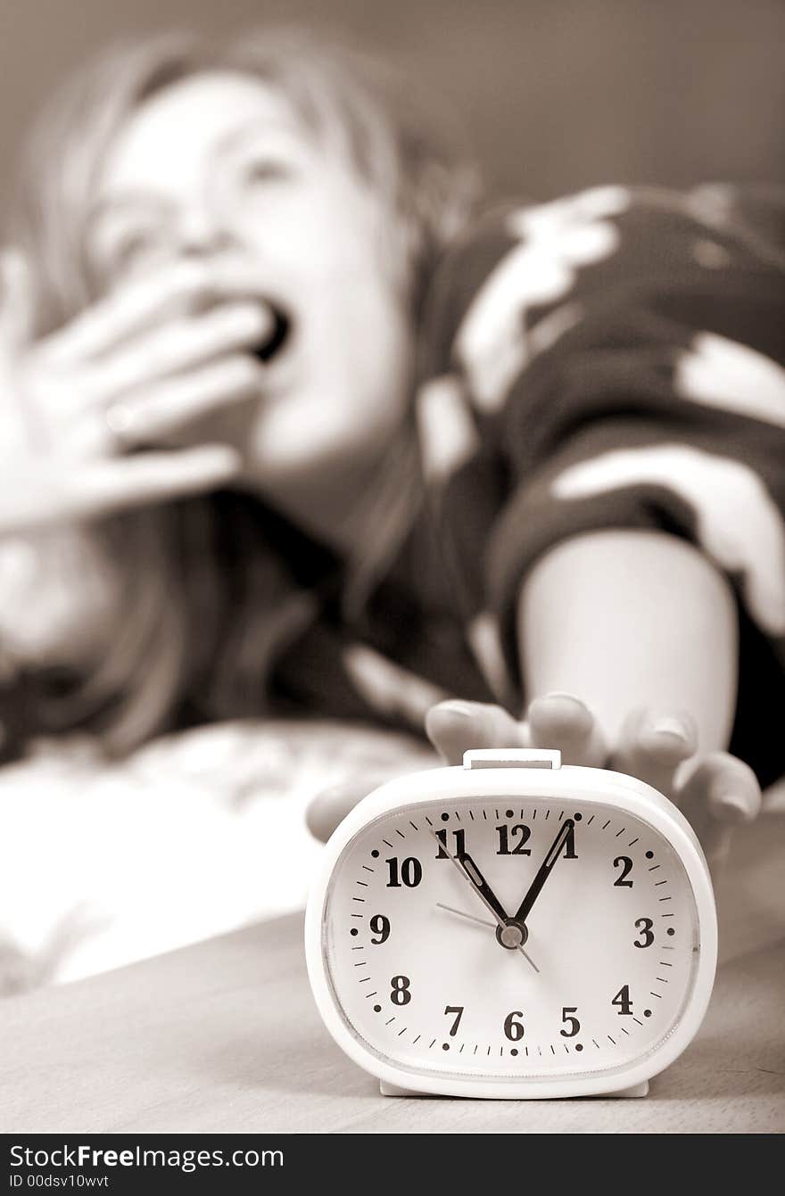 Sleepy woman shuts off alarm clock. Sleepy woman shuts off alarm clock