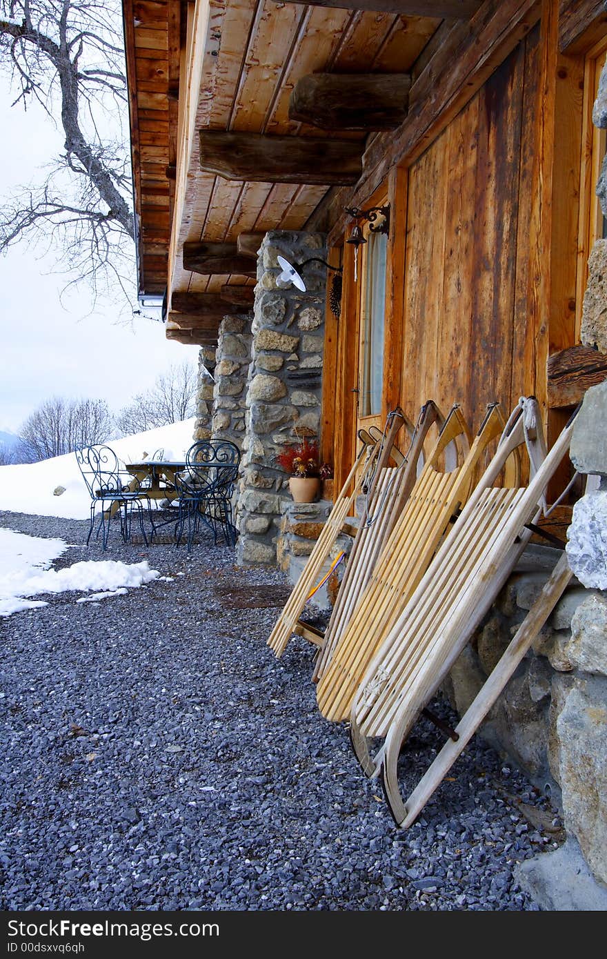 Old wooden sledges in front a typical chalet in the alps. Old wooden sledges in front a typical chalet in the alps