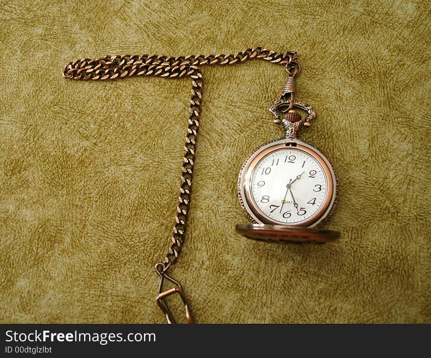 Close-up of old golden clock on vintage background with letter T (which means time)