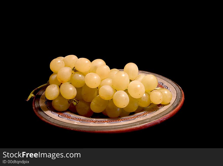 A bunch of white grapes on a plate, isolated on black