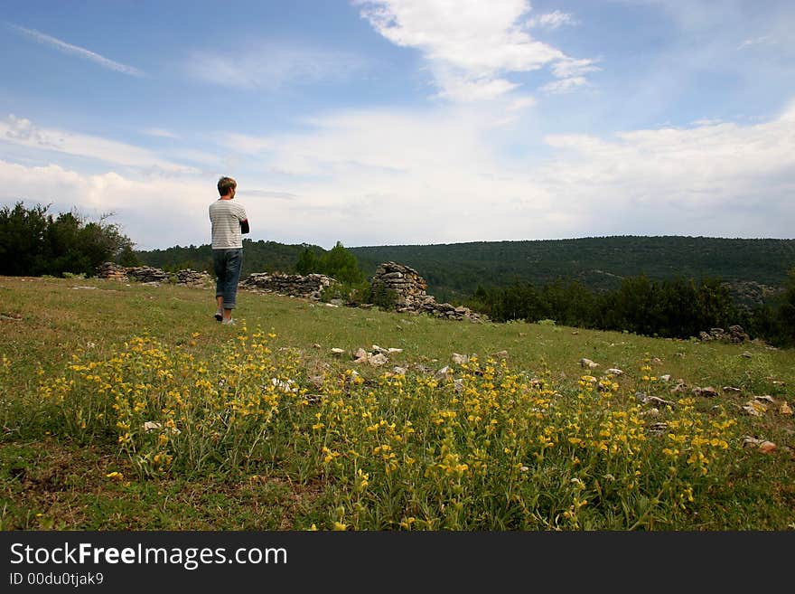 Young guy on top of a mountain looking down into the valley enjoying the beautiful view. Young guy on top of a mountain looking down into the valley enjoying the beautiful view