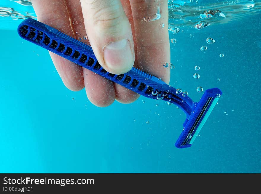 A hand cleaning razor in water - blue background