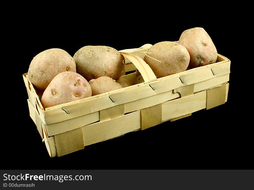 Some red potatoes put in a wood basket on the black backround. Some red potatoes put in a wood basket on the black backround