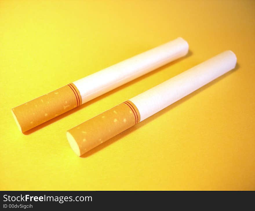 Two cigarettes on a yellow background