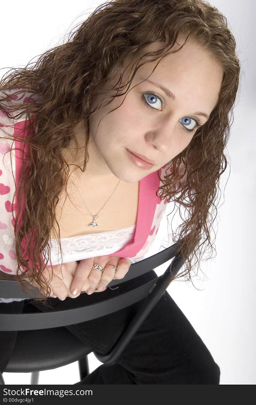 Pretty young brunette woman with curly hair and large blue eyes, seated. Pretty young brunette woman with curly hair and large blue eyes, seated