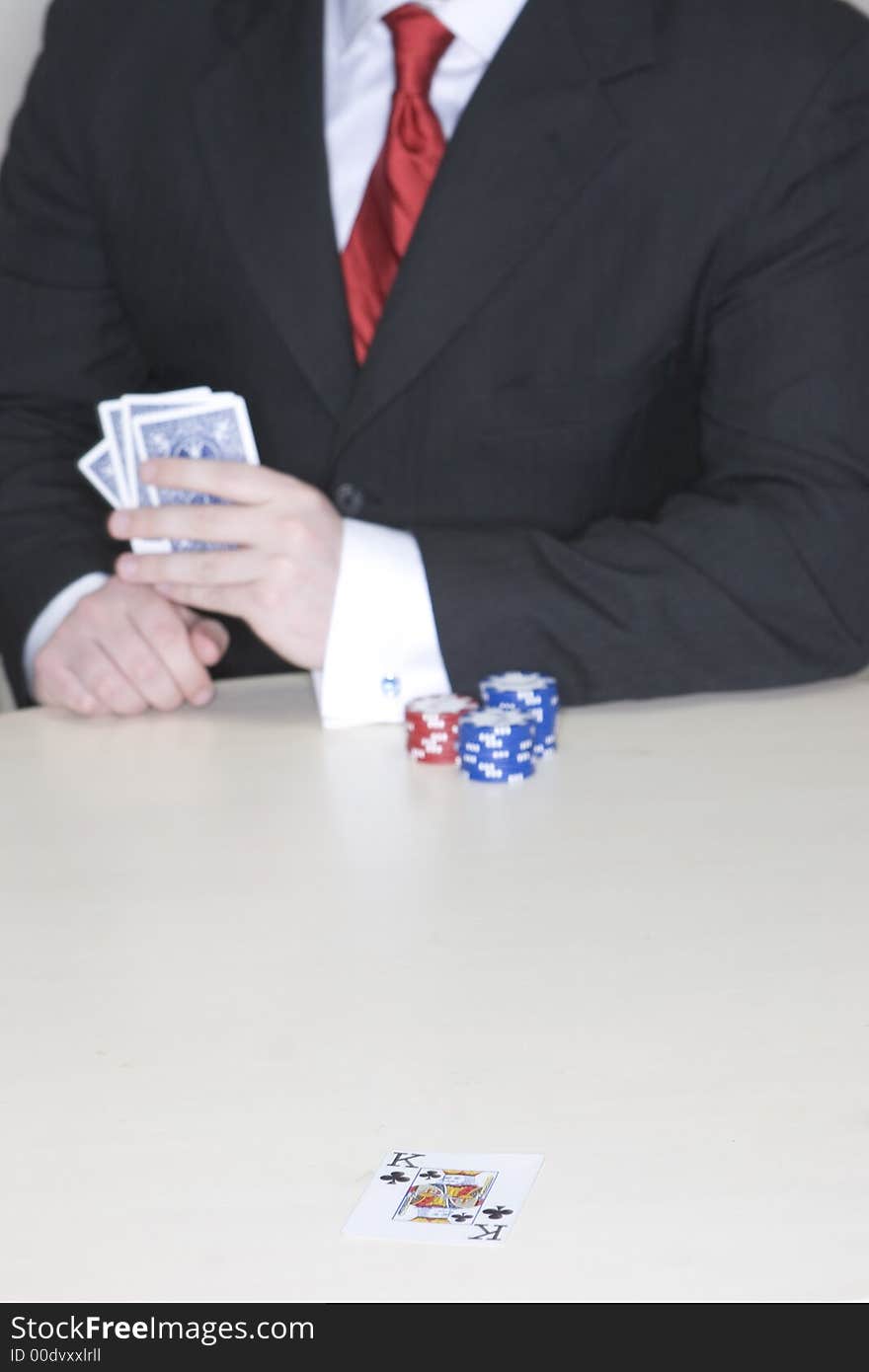 Man holding a hand of poker cards while sitting at a table playing poker. Man holding a hand of poker cards while sitting at a table playing poker