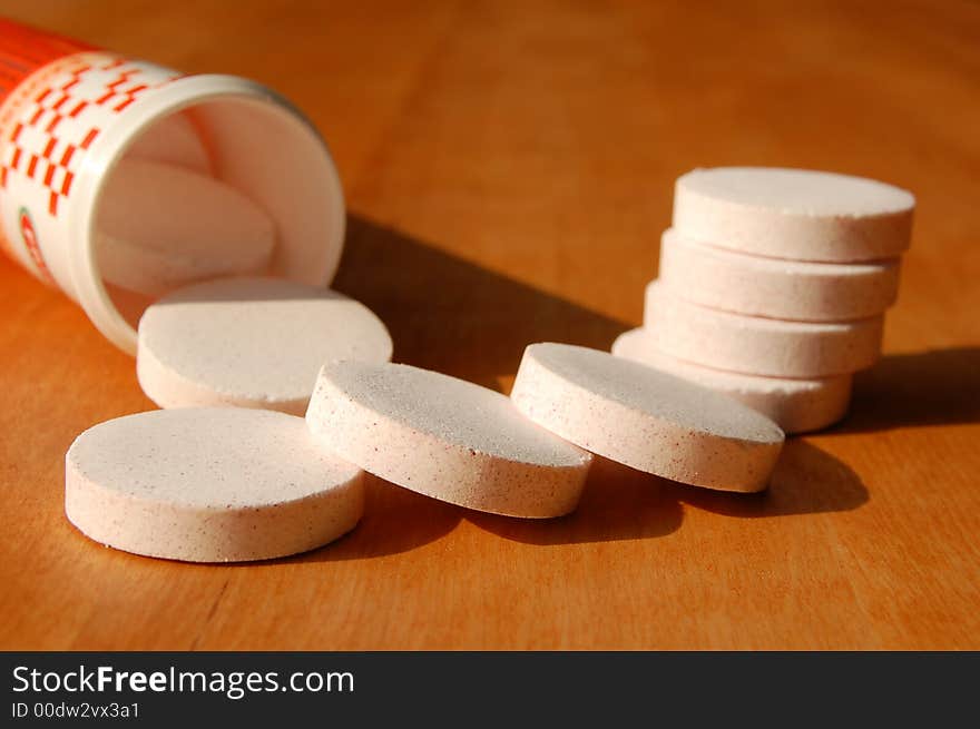 Large pills with opened tube on brown background in hard light. Large pills with opened tube on brown background in hard light