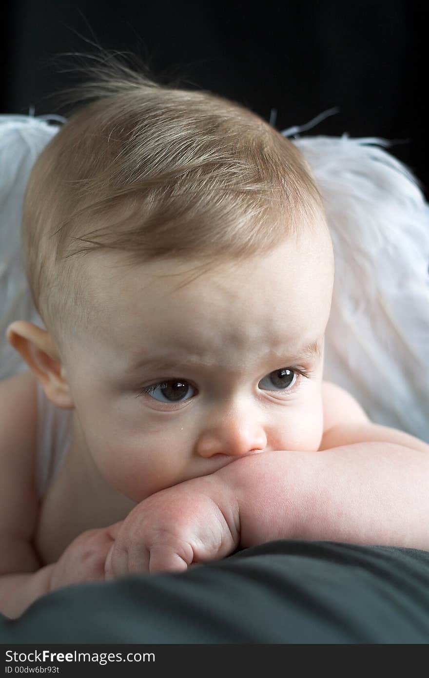 Image of an adorable baby wearing angel wings, in front of a black background. Image of an adorable baby wearing angel wings, in front of a black background