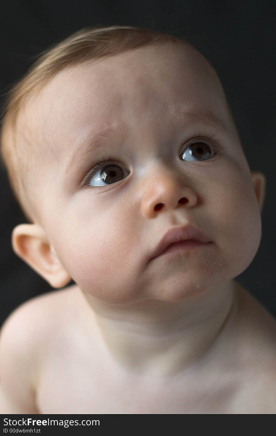 Image of beautiful 10 month old baby boy sitting in front of a black background. Image of beautiful 10 month old baby boy sitting in front of a black background