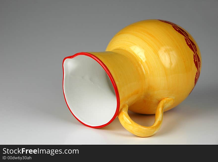 Ceramic jug in yellow and red on neutral background