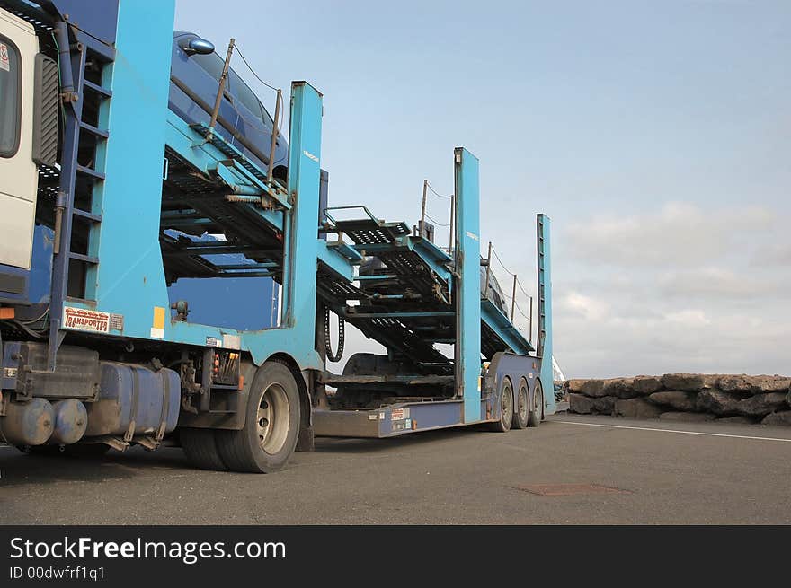 A semi truck car transporter parked up with 2 cars onboard.