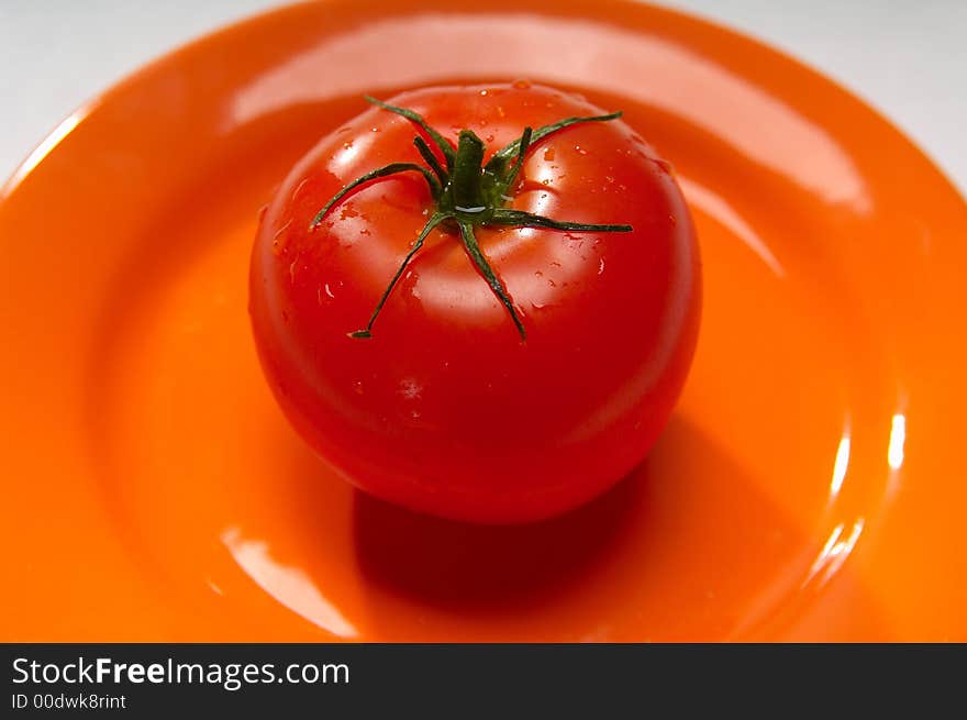 Red tomato on orange plate