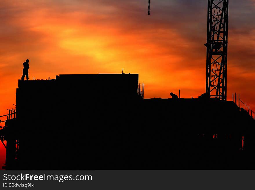 Beautiful sky at sunrise in city. Building under construction and workers at top of the building. Beautiful sky at sunrise in city. Building under construction and workers at top of the building.