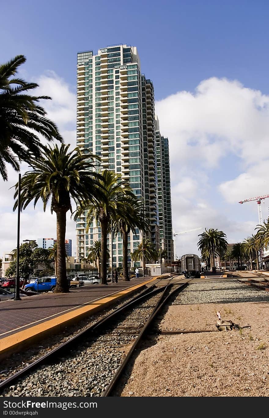 Train leaving station, with high-rise luxury condos and palm trees in the background. Train leaving station, with high-rise luxury condos and palm trees in the background