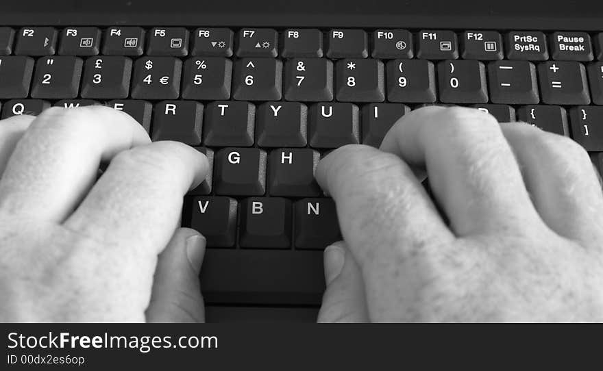 Close-up of businessman's hands typing on laptop's keyboard. Black and white image.