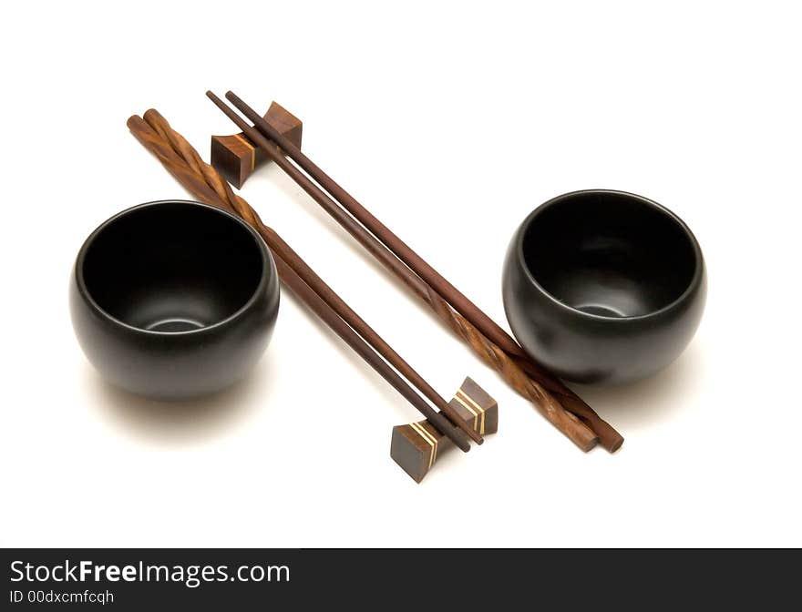 Wooden chopsticks and black tea cups over white. Wooden chopsticks and black tea cups over white.