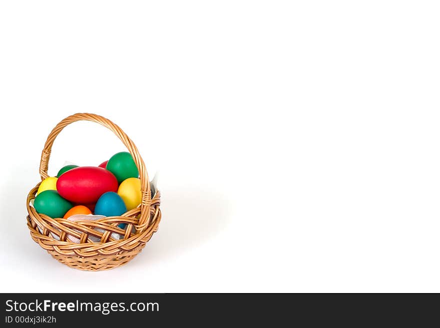 A woven basket with multi colored eggs over white background. A woven basket with multi colored eggs over white background