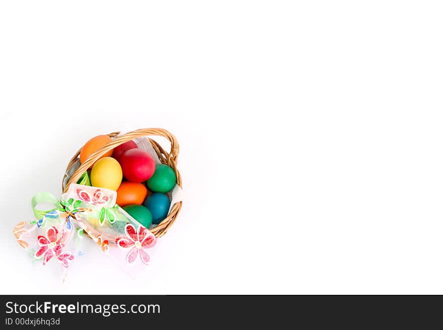 A woven basket with bow and multi colored eggs inside, over white background. A woven basket with bow and multi colored eggs inside, over white background