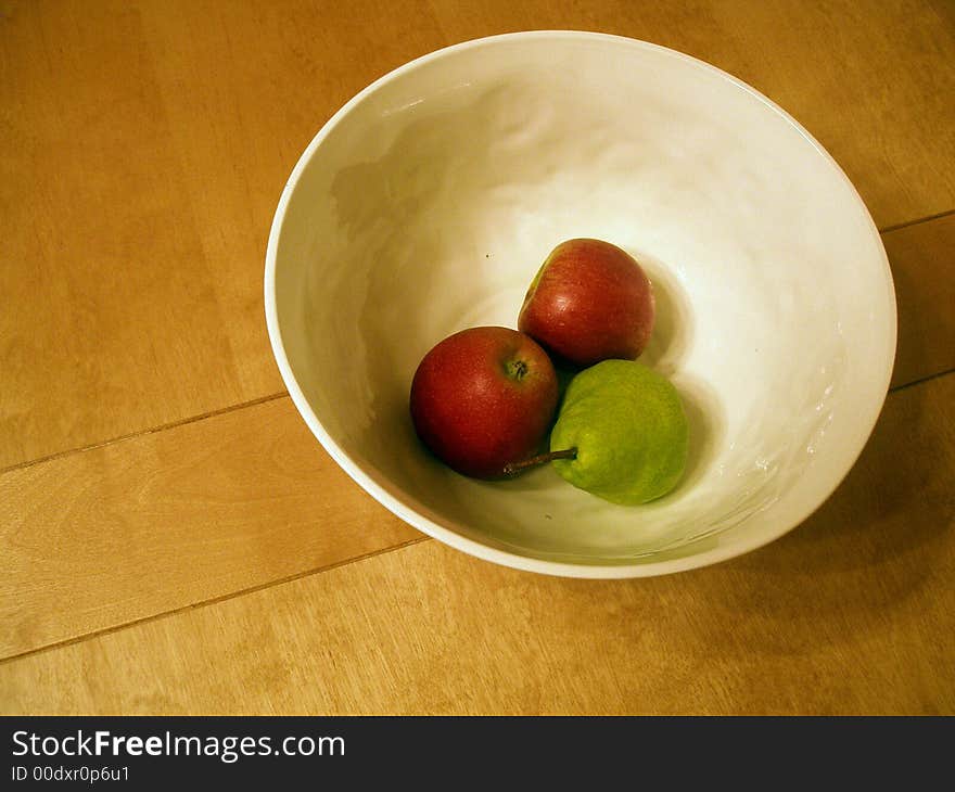 A bowl of fruit on a solid wood table. A bowl of fruit on a solid wood table