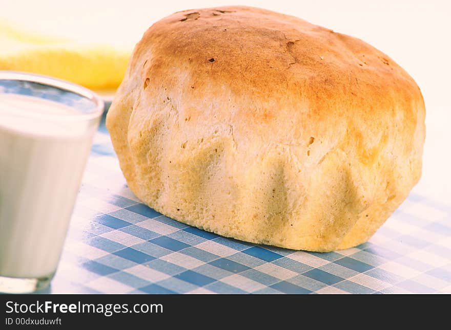 Yellow napkin, loaf  bread and glass of milk lay on dark-blue cloths