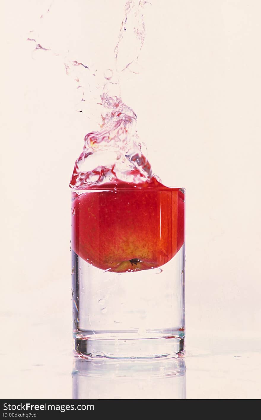 Composition from falling red apple in glass with water on white background. Composition from falling red apple in glass with water on white background