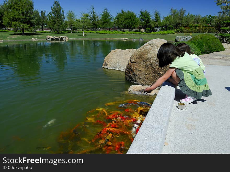 Girls feeding Koi fish at a Japanese Tea Garden in Phoenix, Arizona