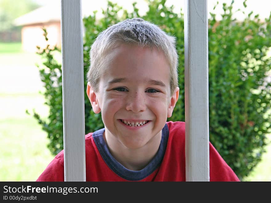 A Boy smiling between wooden railings