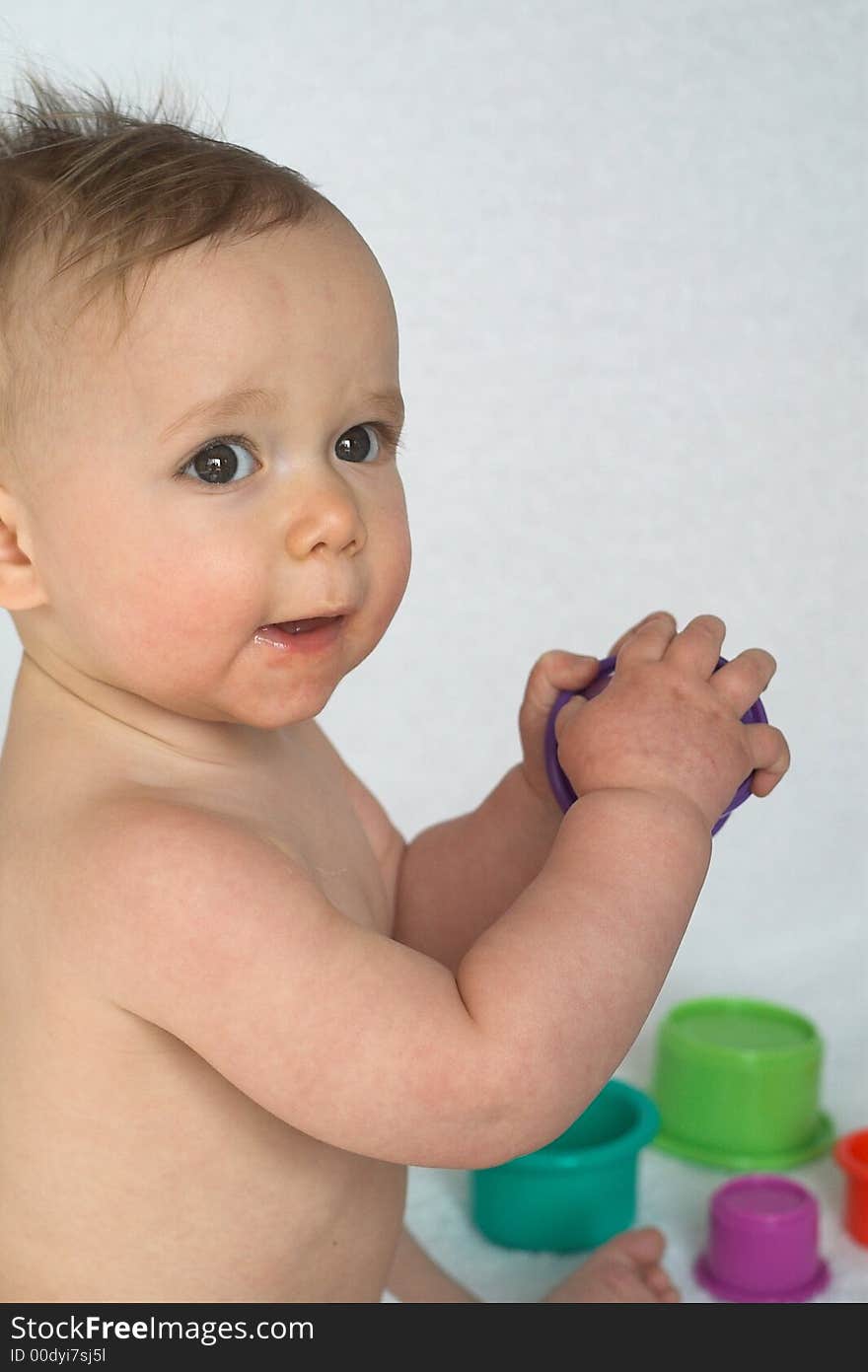 Image of adorable baby playing with stacking cups, sitting in front of a white background. Image of adorable baby playing with stacking cups, sitting in front of a white background